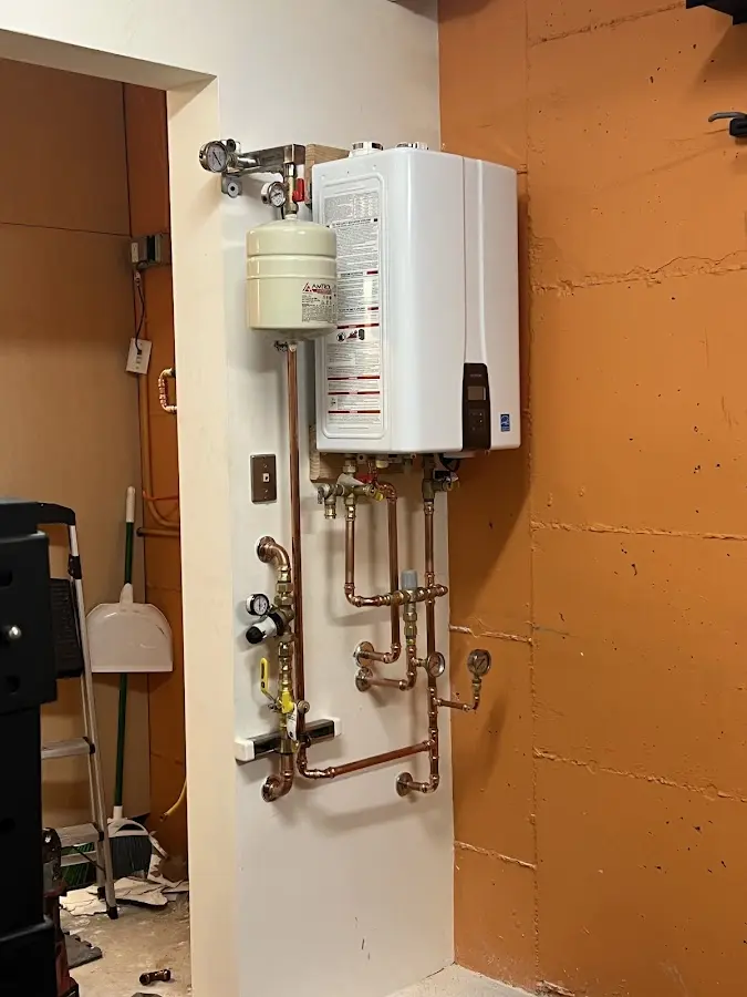Plumbing technician inspecting water heater connections in Litchfield